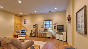 A cozy living room with a wooden floor, a sofa, a desk, and a television.