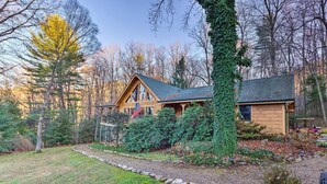 A wooden cabin with a sloped roof, surrounded by trees and a well-maintained garden.