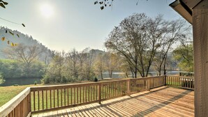 Una terraza de madera con barandilla que da a un lago y árboles.