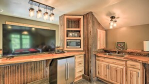 A kitchen with a large flat-screen TV, a built-in microwave, and a stainless steel refrigerator. - Waterfront Log Home w/ 95 Acres on Yaak River (Troy)