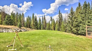 A grassy field with croquet equipment and a blue ball on a metal stand. - Waterfront Log Home w/ 95 Acres on Yaak River (Troy)