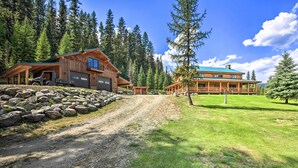 A log cabin with a covered driveway and a large front porch. - Waterfront Log Home w/ 95 Acres on Yaak River (Troy)