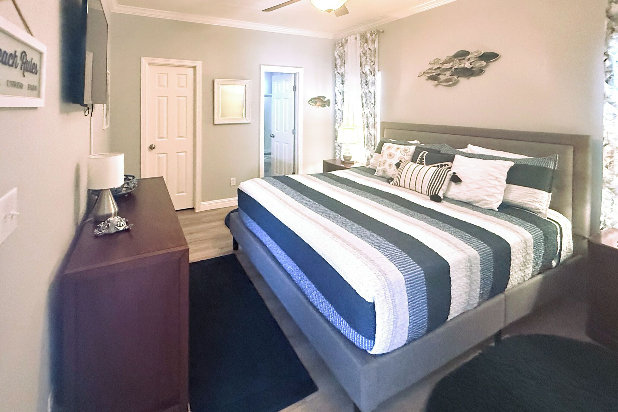 A bedroom with a bed, a dresser, a lamp, and a door.