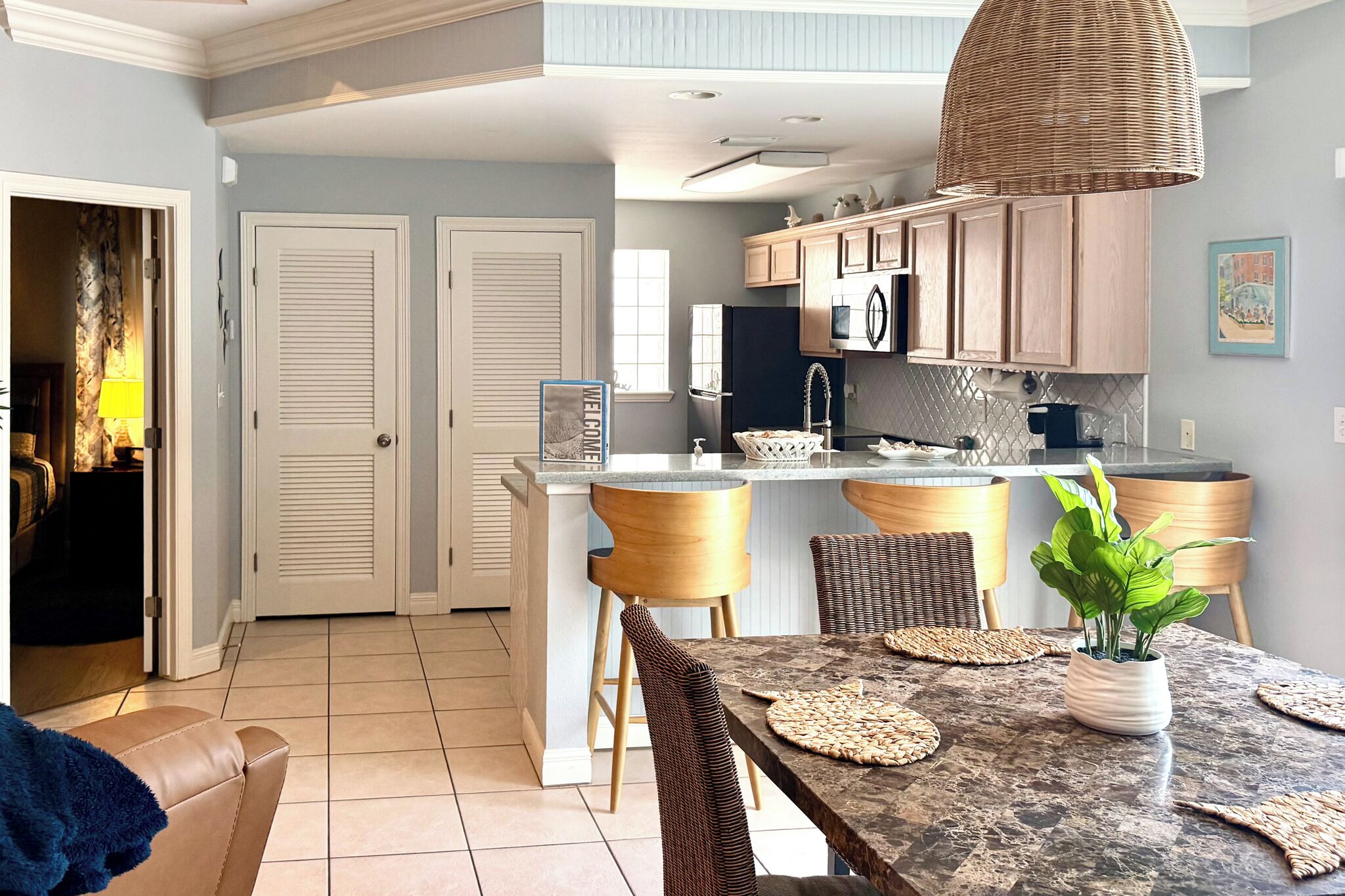 A modern kitchen with a central island, wooden cabinets, and a dining area with a table and chairs.