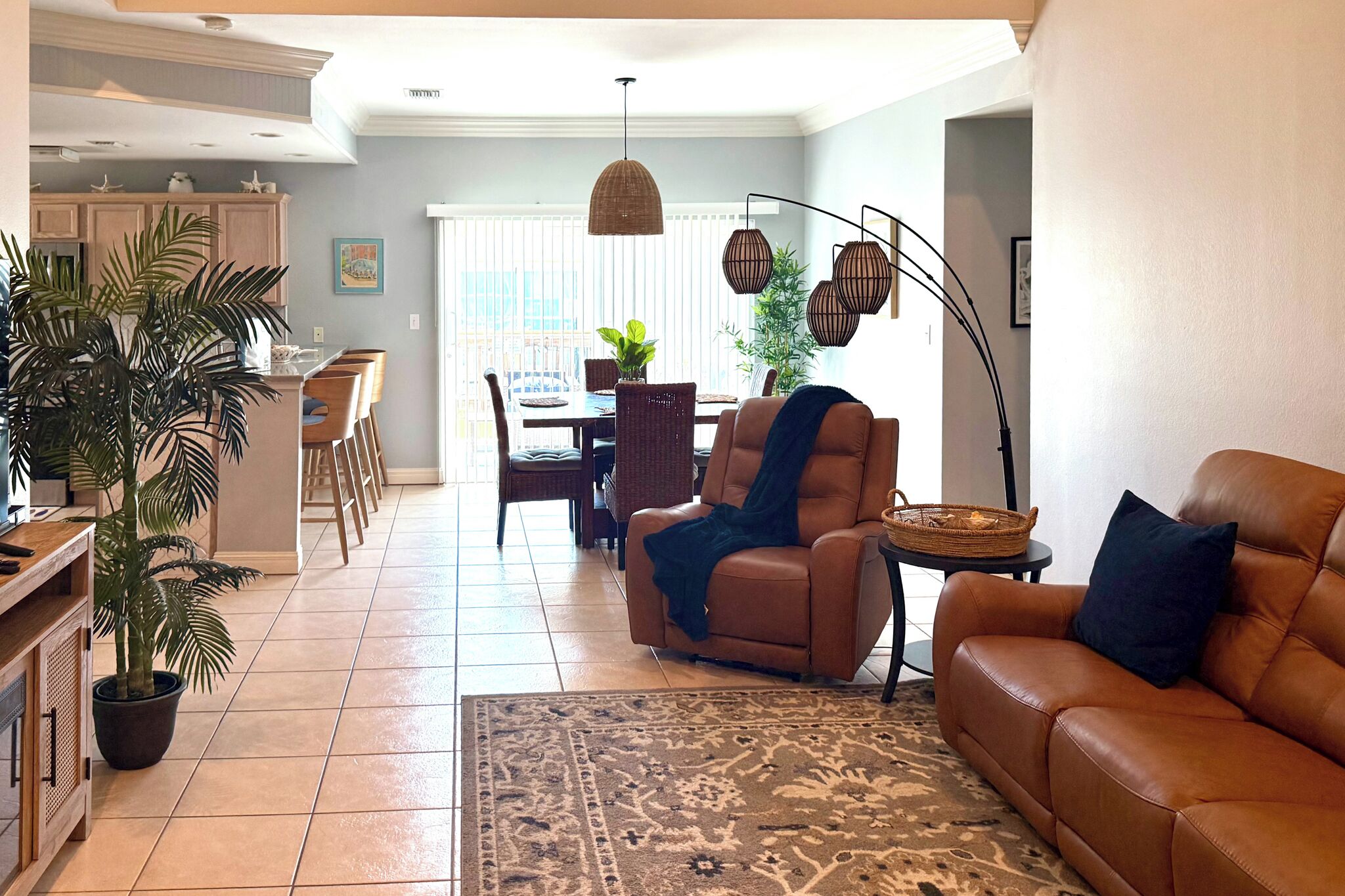 Un salon avec un canapé en cuir marron, un coin repas avec une table et des chaises, et une cuisine avec un comptoir et des tabourets.