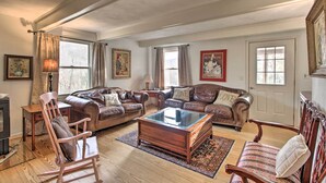 A spacious living room with leather sofas, a glass coffee table, wooden chairs, and a fireplace. - Spacious Faber Home w/ Yard, Steps to Winery! (Faber)