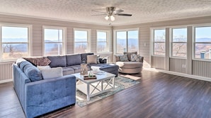 A spacious living room with a large window, a ceiling fan, and a view of mountains. - North Carolina Vacation Rental w/ Fire Pit & Grill (Leicester)