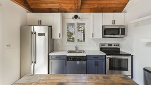 A modern kitchen with white cabinets, a stainless steel refrigerator, a microwave, an oven, and a dishwasher. - Family Friendly 5 Bedroom, Walk to Town, Beach & Ferry (Tisbury)