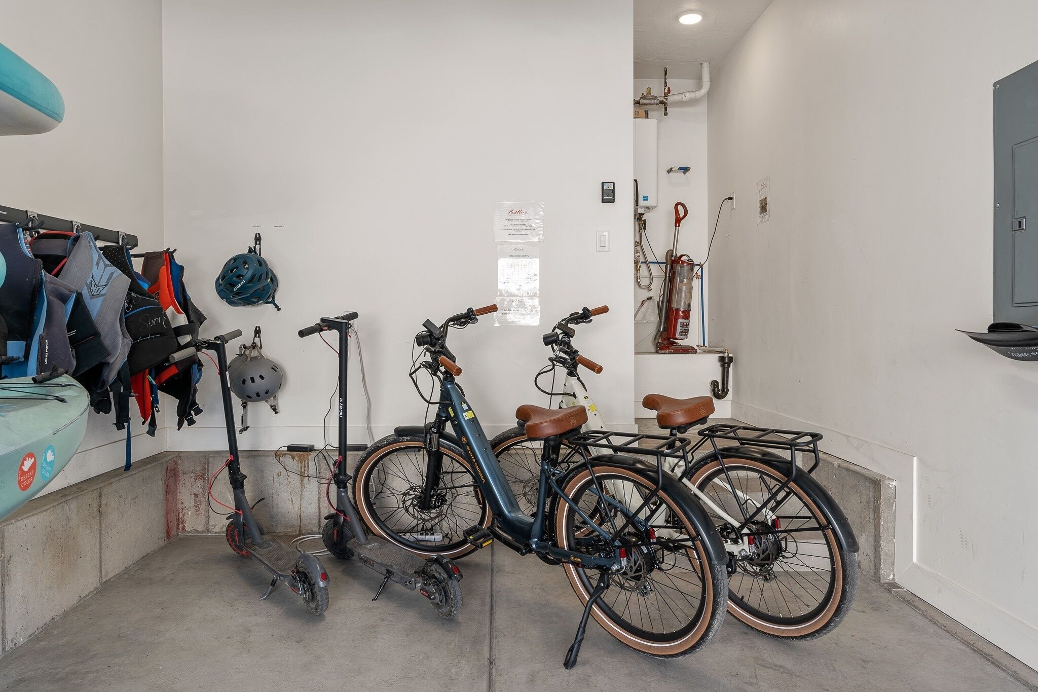A bicycle storage area with two bicycles, a helmet, and a scooter.