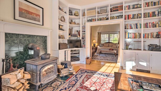 A cozy living room with a fireplace, a large bookshelf, and a comfortable seating area. - Private Home w/ Hot Tub Near Jay Peak Slopes (Montgomery Center)