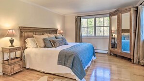 A bedroom with a large bed, a nightstand with a lamp, a window with curtains, and a mirror. - Private Home w/ Hot Tub Near Jay Peak Slopes (Montgomery Center)