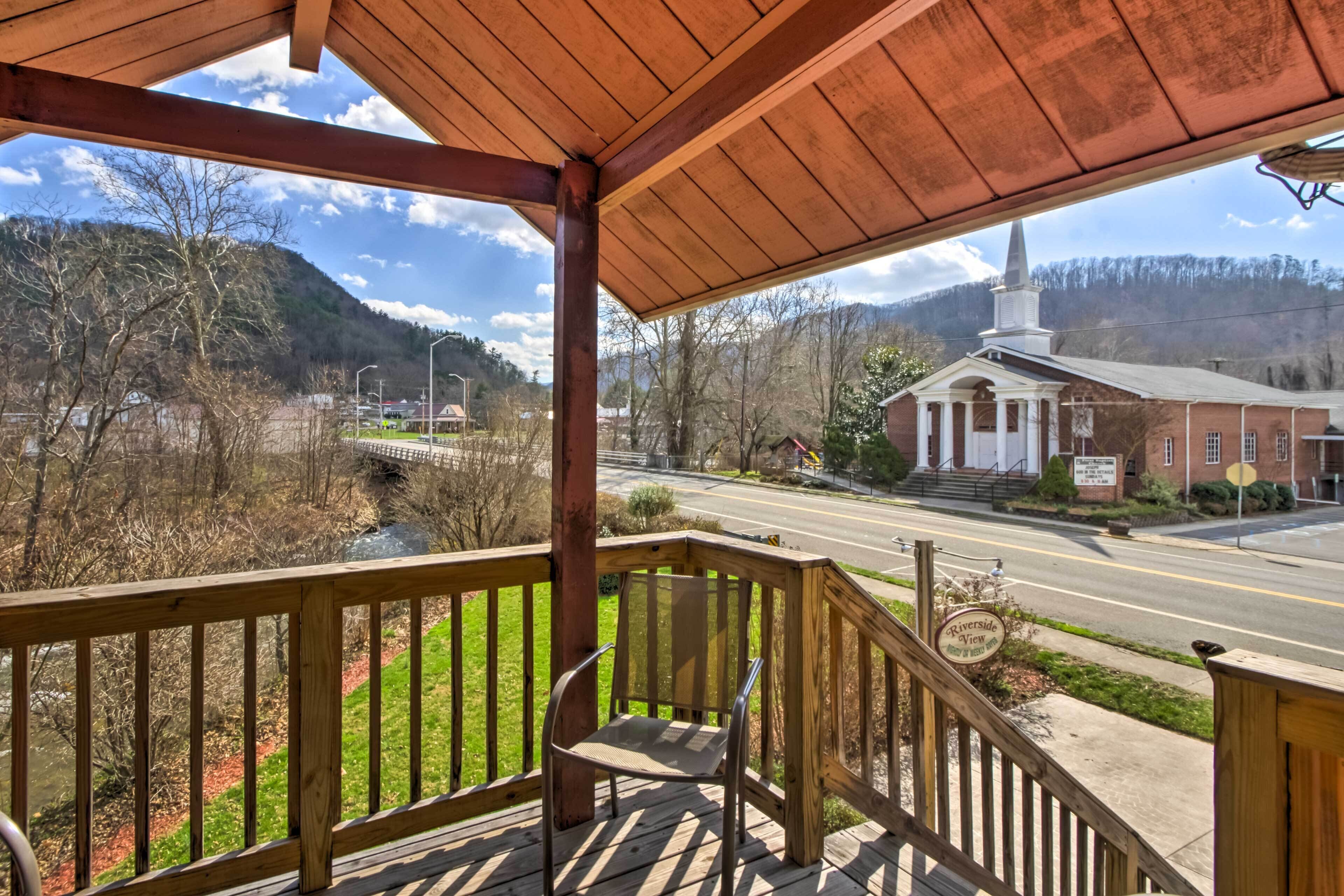 A wooden porch with a view of a church and a road.