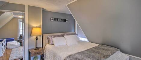 A bedroom with a bed, a nightstand, a lamp, a wall sign, and a ceiling fan.