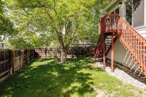 Enjoy the serene atmosphere of this backyard with a staircase leading to a second-story deck.