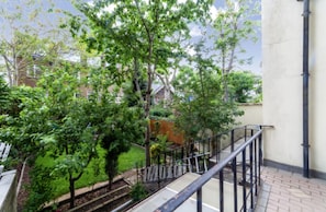 Stroll through the serene garden, surrounded by lush greenery and a staircase leading up to a balcony.
