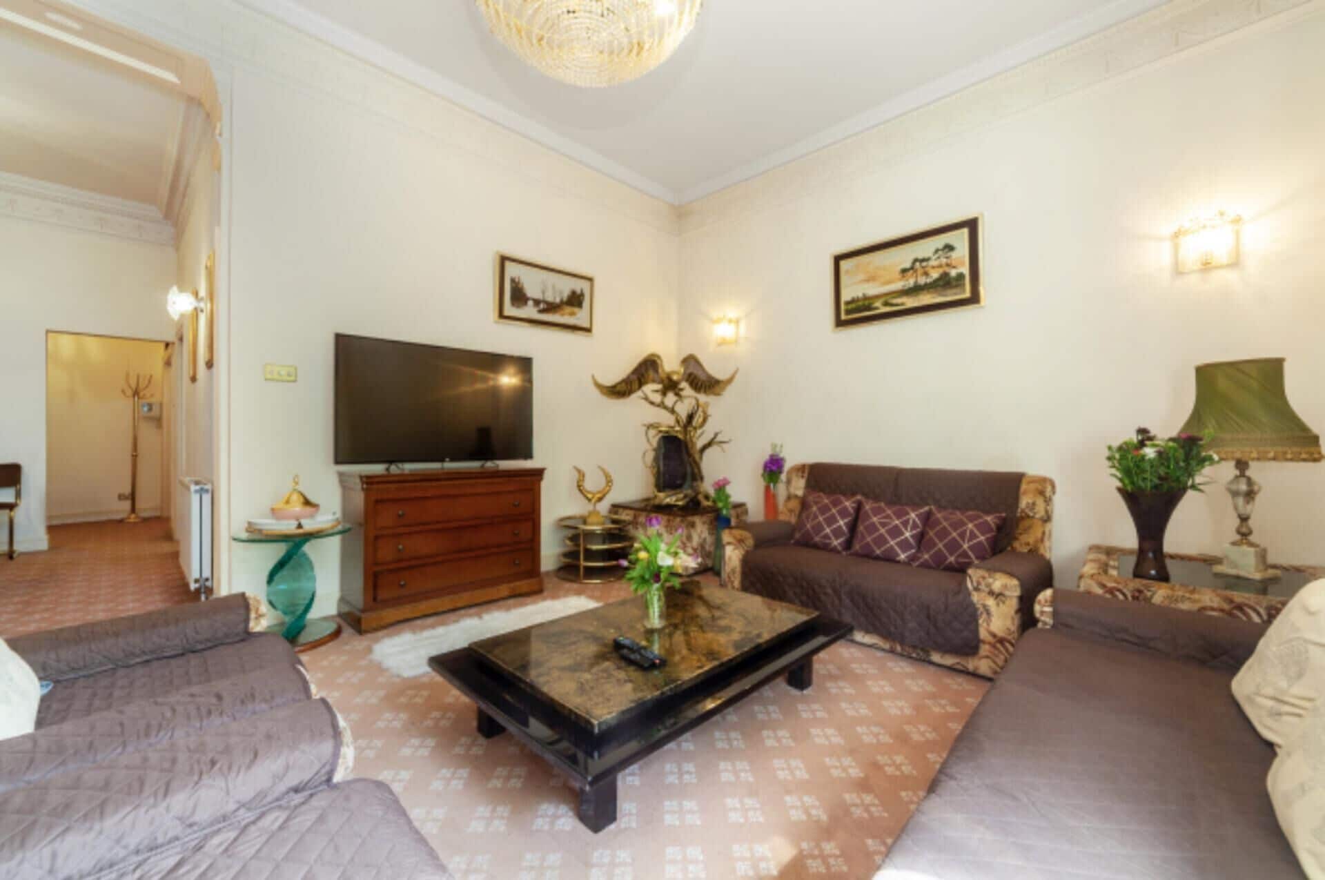 A living room with a sofa, a coffee table, a television, and decorative items.