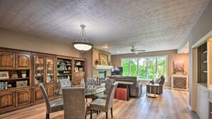 A spacious living room with a fireplace, a dining area with a glass table, and a large wooden cabinet with glass doors. - Resort-style Condo w/ Balcony on Lake Keowee (Salem)