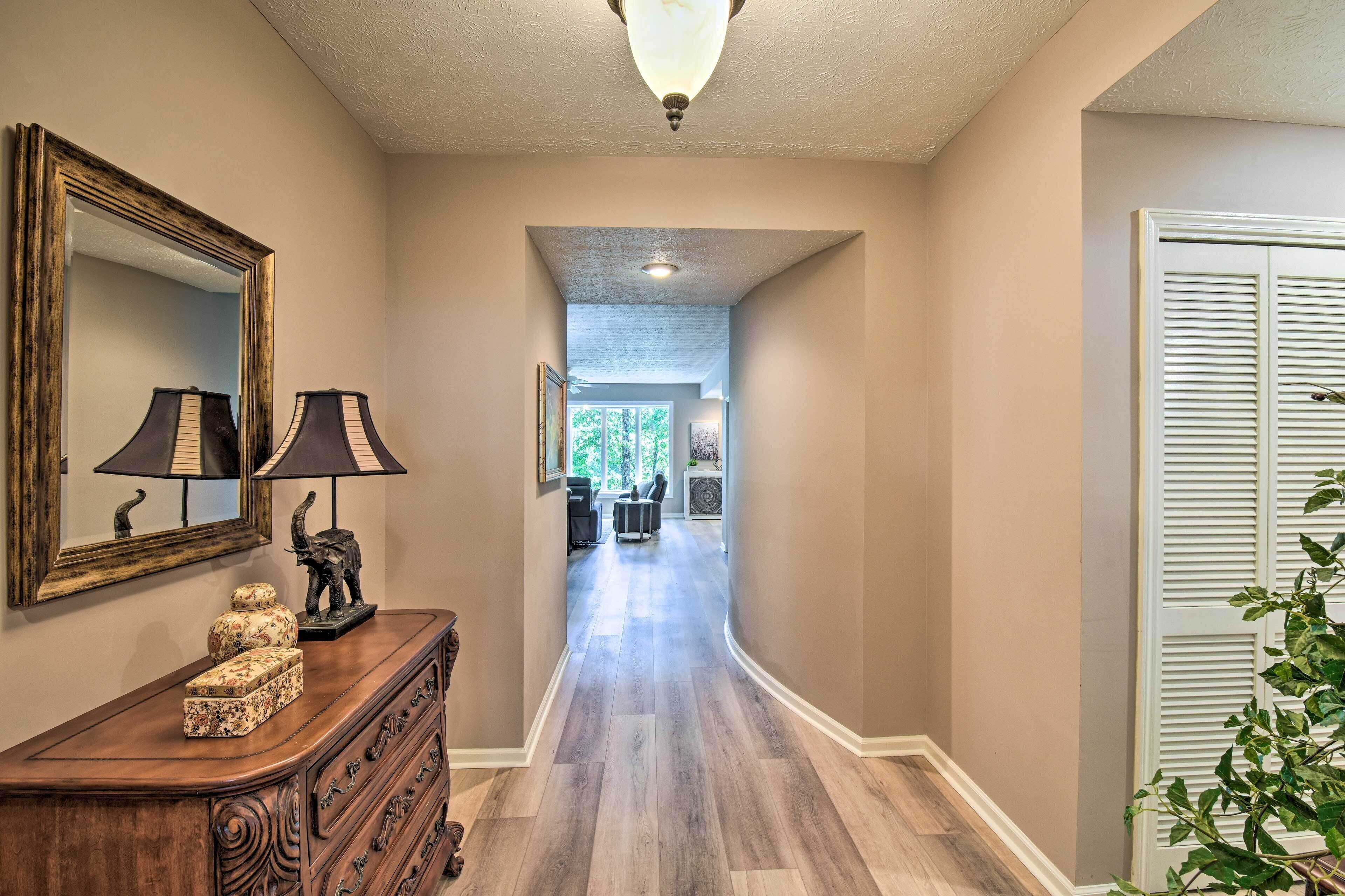 A hallway with a wooden dresser, a mirror, and a lamp.