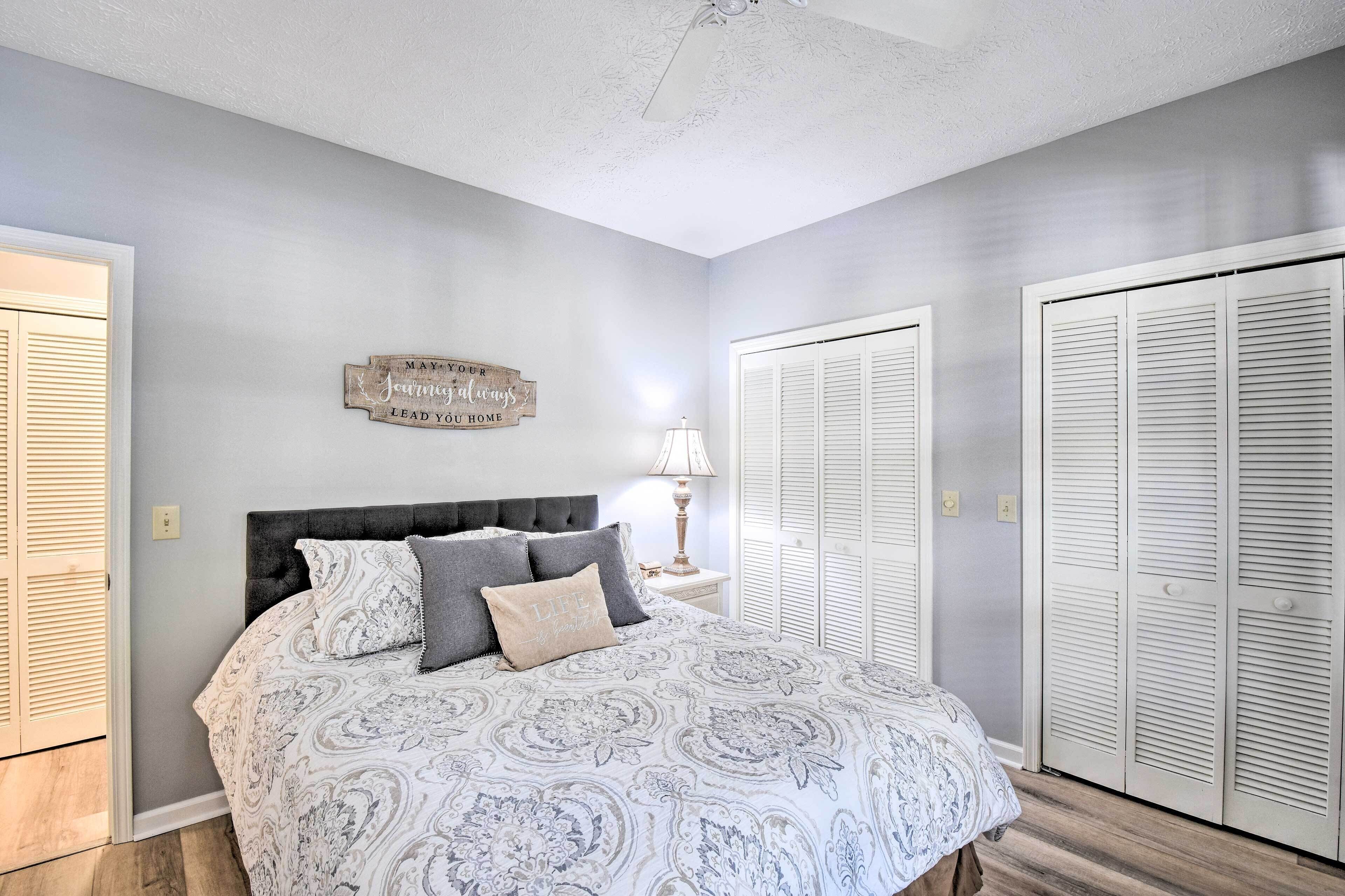 Une chambre à coucher avec un lit, une table de chevet, une lampe et un panneau fixé au mur.