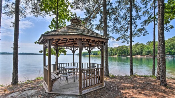 A wooden gazebo with a roof, surrounded by trees, overlooking a lake. - Resort-style Condo w/ Balcony on Lake Keowee (Salem)