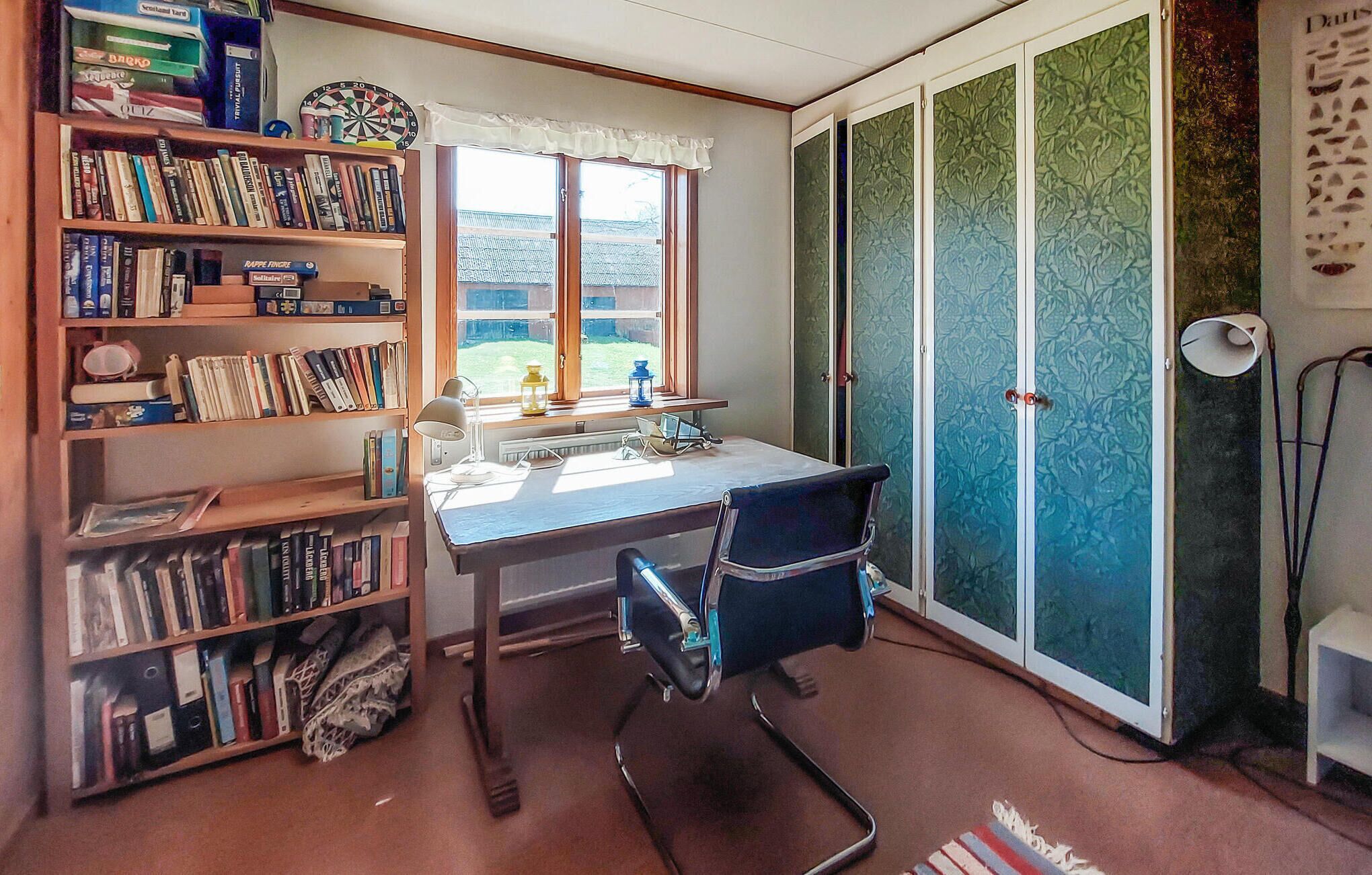 Une pièce comprenant un bureau, une chaise, une bibliothèque et une porte coulissante avec des vitres décorées.