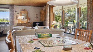 A cozy living room with a board game set up on a table, a fireplace, and large windows with a view of greenery. - Nice home in Bækmarksbro with WiFi (Bækmarksbro)
