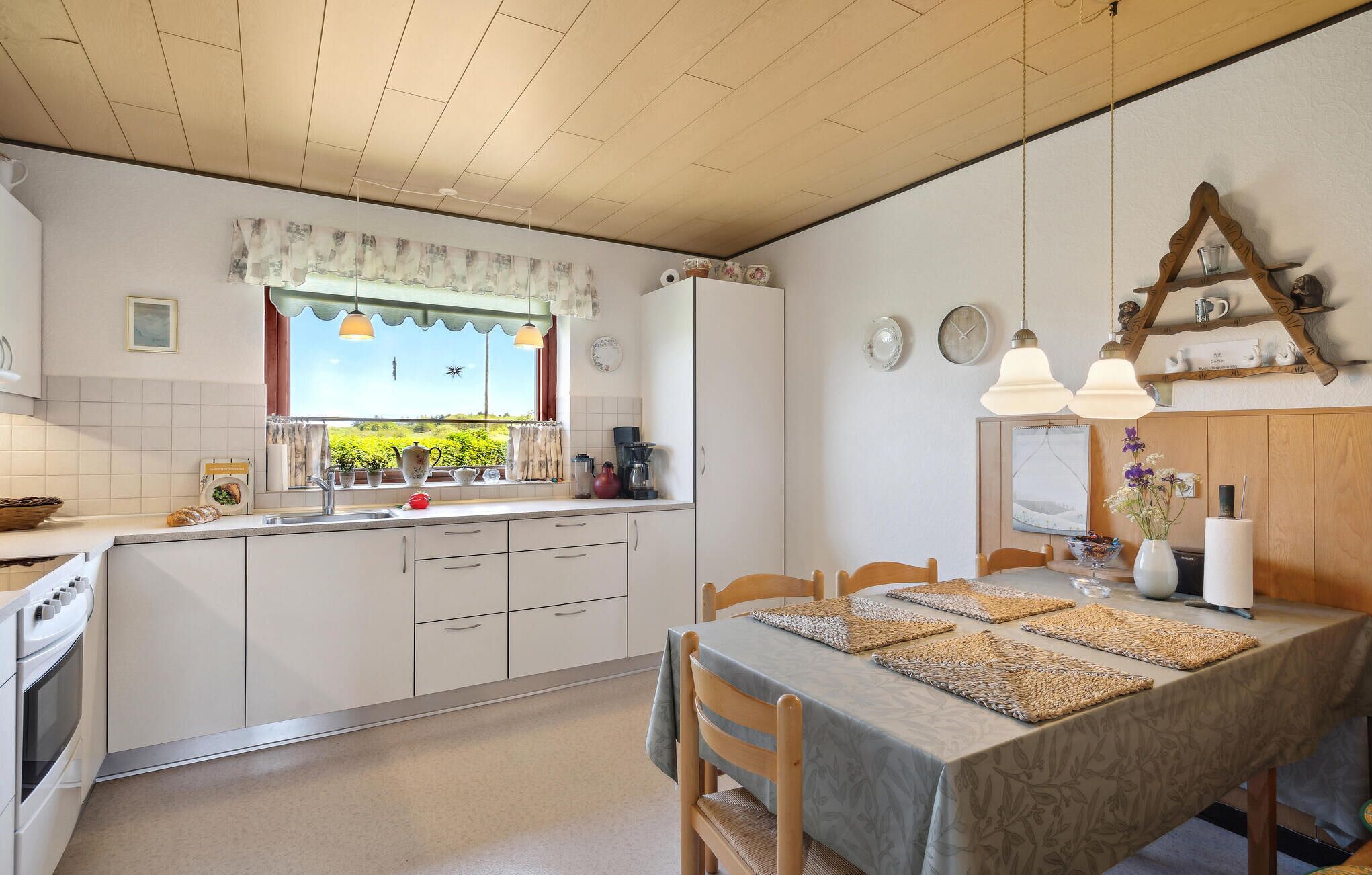 Una cocina con comedor, armarios de madera, estufa y ventana con vista a vegetación.