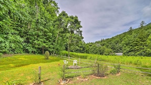 A rural landscape with a fenced area, a small structure, and a chair. - Scenic Creekside Cabin w/ Wraparound Porch! (Highlands)