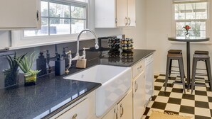 A kitchen with a black countertop, white cabinets, a sink, and a checkered floor. - Downtown Kirkland Rental: Steps to Lake Washington (Kirkland)