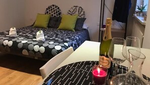 Een hotelkamer met een bed, een tafel met champagne, glazen en een kaars.