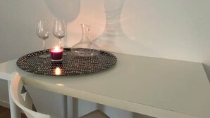 Een tafel met een kaars, twee wijnglazen en een bloevas.
