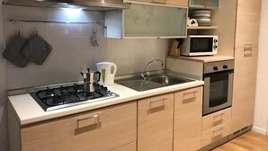 Een moderne keuken met een gasfornuis, een roestvrijstalen afzuigkap, een magnetron, een oven en houten keukenkastjes.