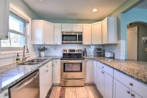 A modern kitchen with white cabinets, stainless steel appliances, and granite countertops.