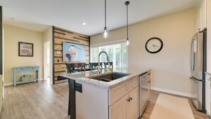 A modern kitchen with a central island, stainless steel appliances, and a dining area with a wooden table and chairs. - Beachfront De Tour Village Townhome w/ Patio! (De Tour Village)