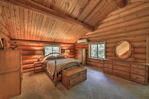 Ein Schlafzimmer in einer Blockhütte mit einem hölzernen Bett, einer Kommode und einem Spiegel.