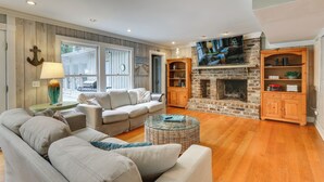 Una sala de estar con chimenea, un sofá, una mesa de centro y una televisión.
