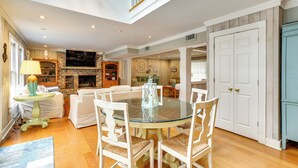 Un salón espacioso con chimenea, un comedor con mesa de vidrio y una cocina con armarios de madera.