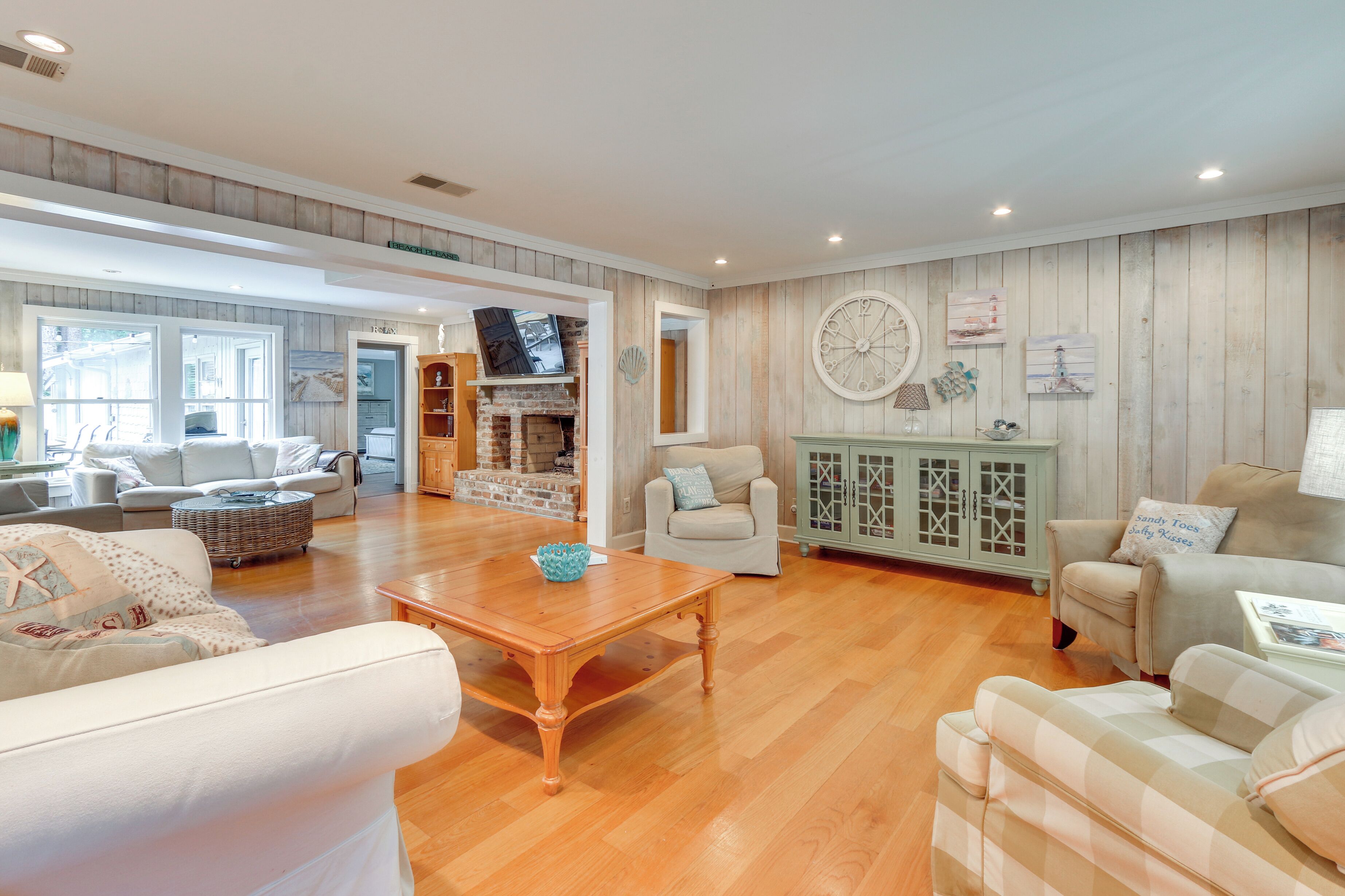 A spacious living room with wooden flooring, a fireplace, and a television.