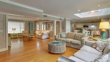 A spacious living room with a large sofa, a round coffee table, and a dining area with a table and chairs.
