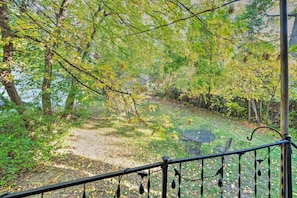 A garden with a metal table and chairs, surrounded by trees and a fence.