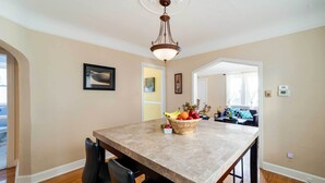 A dining area with a marble table, black chairs, a fruit bowl, and a hanging light fixture. - Ferndale Apartment w/ Yard - Near the Detroit Zoo! (Ferndale)