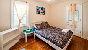 A bedroom with a bed, a desk, a chair, a ceiling fan, and a window with curtains. - Ferndale Apartment w/ Yard - Near the Detroit Zoo! (Ferndale)