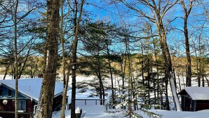 A cabin surrounded by tall trees in a snowy landscape. - Waterfront Escape w/ Kayak, Paddle Boards, & Sauna (Casco)