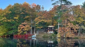 A cabin by a lake surrounded by autumn-colored trees. - Waterfront Escape w/ Kayak, Paddle Boards, & Sauna (Casco)