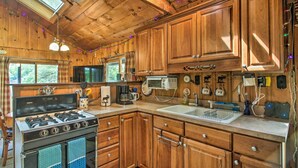 A wooden cabin kitchen with a stove, sink, and cabinets. - Waterfront Escape w/ Kayak, Paddle Boards, & Sauna (Casco)