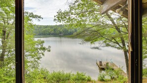A view through a window of a lake with a dock and chairs, surrounded by greenery. - Waterfront Escape w/ Kayak, Paddle Boards, & Sauna (Casco)