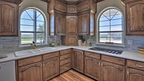 A kitchen with wooden cabinets, a white countertop, and two large arched windows. - Patio & Covered Porch: Spacious Bellevue Home! (Bellevue)