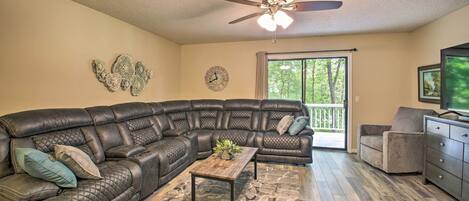 A living room with a sectional sofa, a coffee table, and a ceiling fan.