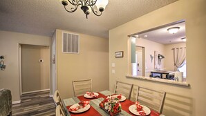 A dining area with a table set for four, chairs, a chandelier, and a mirror on the wall. - Furnished Deck & Grill: Hot Springs House (Hot Springs Village)
