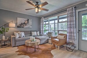 A living room with a grey sofa, a brown leather chair, a round coffee table, and a ceiling fan.